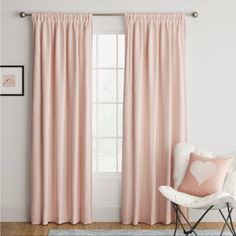 a white chair sitting in front of a window with pink curtains on the windowsill