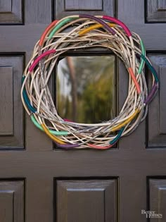 a wreath is hanging on the front door with colorful ribbons around it and an empty mirror