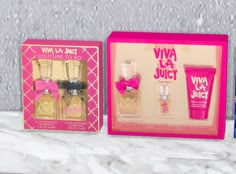 three different types of perfumes in pink and gold boxes on a marble countertop