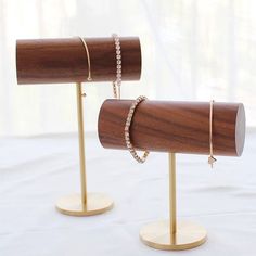 two wooden jewelry stands on top of a white table