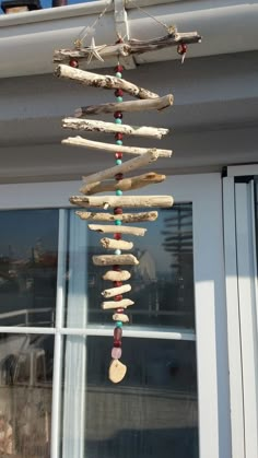 a wind chime hanging from the side of a building with rocks and beads on it