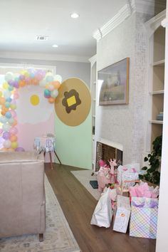 a living room filled with lots of presents on the floor and balloons hanging from the ceiling