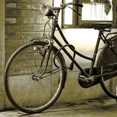 an old bicycle parked next to a brick wall in front of a window and door