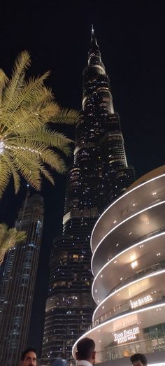 people standing in front of the burj building and palm trees lit up at night