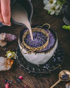 a person pours sugar into a cake with purple flowers on the table next to it