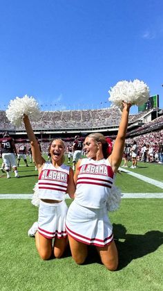 two cheerleaders sitting on the field at a football game