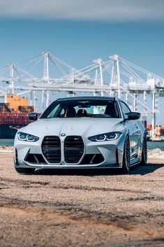 a silver sports car parked in front of a container ship