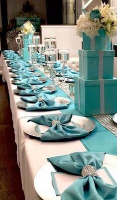 the table is set with blue and white napkins, silverware, and gift boxes