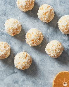 coconut balls and an orange slice on a gray surface with the top half cut off