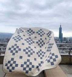 a blanket sitting on top of a wooden bench next to a tall building in the distance