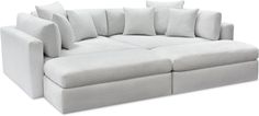 a white couch with lots of pillows on the top and bottom corner, sitting in front of a white background