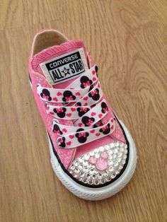 a pair of pink and white shoes with minnie mouse on the side, sitting on top of a wooden floor