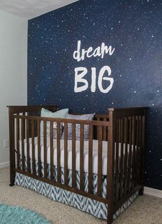 a baby crib in front of a wall with the words dream big written on it