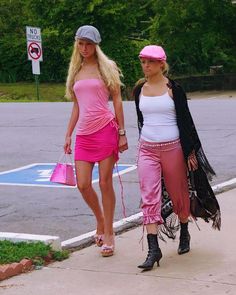 two women walking down the street with one holding a pink purse and another carrying a black bag