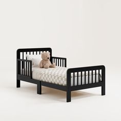 a teddy bear sitting on top of a small black toddler bed with checkered sheets