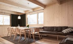 a living room and dining area with wood paneling on the walls, couches, table and chairs