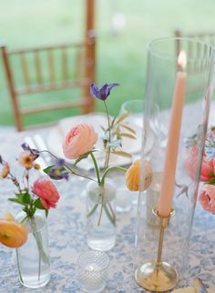 there are flowers in vases and candles on the table with one candle lit up