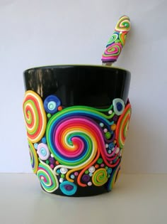 a black cup with colorful swirls on it and a toothbrush in the holder