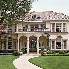 a large white house sitting on top of a lush green field