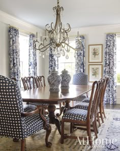 a dining room table with blue and white chairs in front of the chandelier