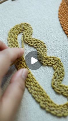 someone is stitching a chain on a piece of fabric with their hands and fingers