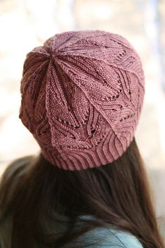 a woman wearing a pink knitted hat looking down at her hair in the wind