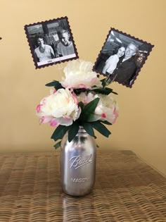 a vase filled with flowers sitting on top of a table next to two framed pictures