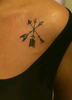 an arrow tattoo on the back of a woman's shoulder is shown in black ink