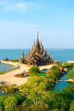 an island in the middle of water surrounded by trees and sand, with many spires