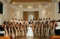 a large group of people in gold dresses posing for a wedding photo with the bride and groom