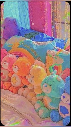 there are many teddy bears on the bed together and one is pink, blue, yellow, green, orange