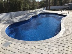 an empty swimming pool surrounded by brick pavers