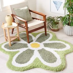 a green and white rug with a flower design on the floor next to a chair