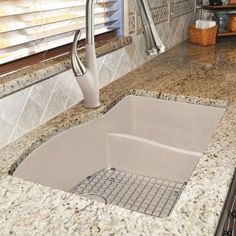 a kitchen sink under a faucet in a granite counter top next to a window