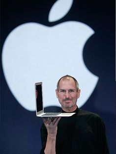 steve jobs holding up an apple laptop