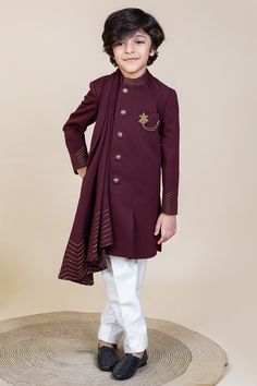 Featuring a wine angrakha indo-western jacket in poly wool base with gold zardosi and resham dhaga motifs embroidery including an attached drape. It is paired with contrasting off-white slim pants.     FIT: True to size.   COMPOSITION: Poly wool.   CARE: Dry clean only. Wedding Dress For Boys, Kids Designer Outfits, Stylish Boy Clothes, Motifs Embroidery, Kids Indian Wear, Wedding Outfit For Boys, Kids Party Wear Dresses, Ethnic Wear Indian, Pants For Boys