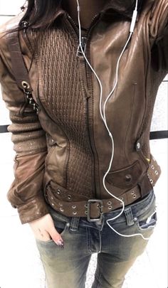 a woman with headphones on her ears is standing in front of a wall and looking at the camera