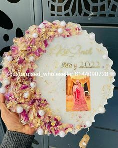 a person holding up a cake with a photo on it and flowers around the edges