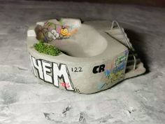 a skateboarder's cement bowl with graffiti on the bottom and grass growing in it