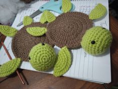 two crocheted turtles are sitting next to each other on top of a notebook