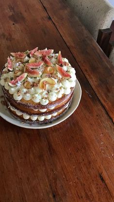 a cake sitting on top of a wooden table covered in frosting and toppings