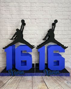 two blue air jordans are on display in front of a white brick wall and wooden floor