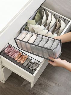 a drawer with several pairs of shoes in it and someone reaching for the shoe box