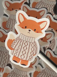 a close up of a sticker with an image of a fox wearing a sweater