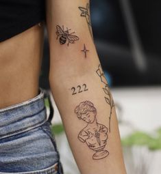 a woman's arm with a tattoo on it that reads 22 and has a bee flying over her shoulder