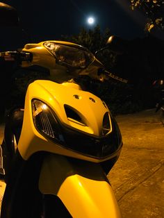 a yellow scooter is parked on the street at night