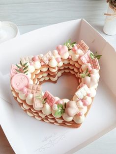 a cake in the shape of a letter decorated with pink and white icing on top of a box