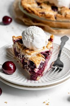 a slice of pie with ice cream on top and cherries around the edges, sitting on a plate