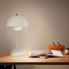 an open book sitting on top of a wooden table next to a lamp and other items