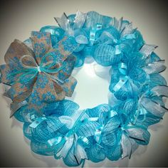 a close up of a wreath made out of blue and silver mesh with a bow